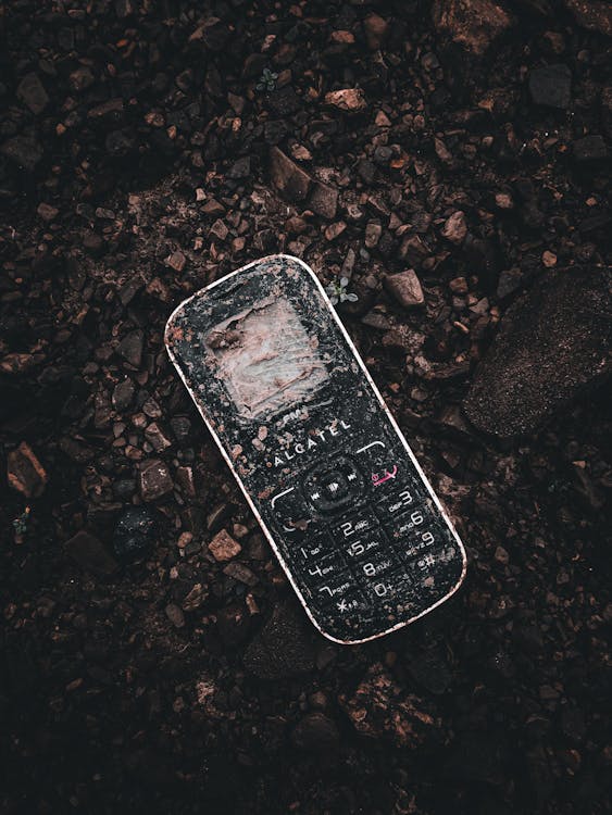 Weathered cellphone lying on the ground representing a lost or stolen phone