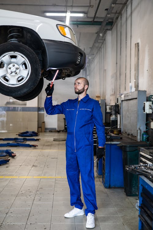 Auto mechanic in blue coverall working underneath a vehicle