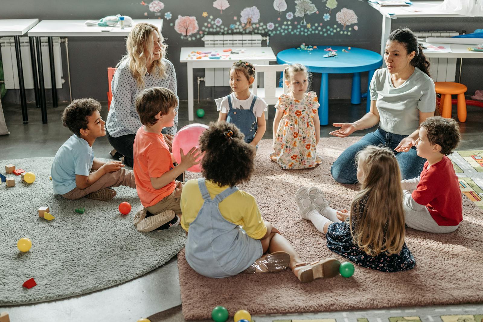 Children in circle time with attentive teachers at a daycare