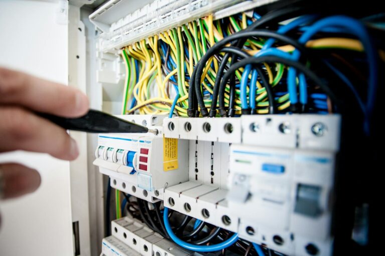 A licensed electrician carefully repairing an opened electrical switchboard