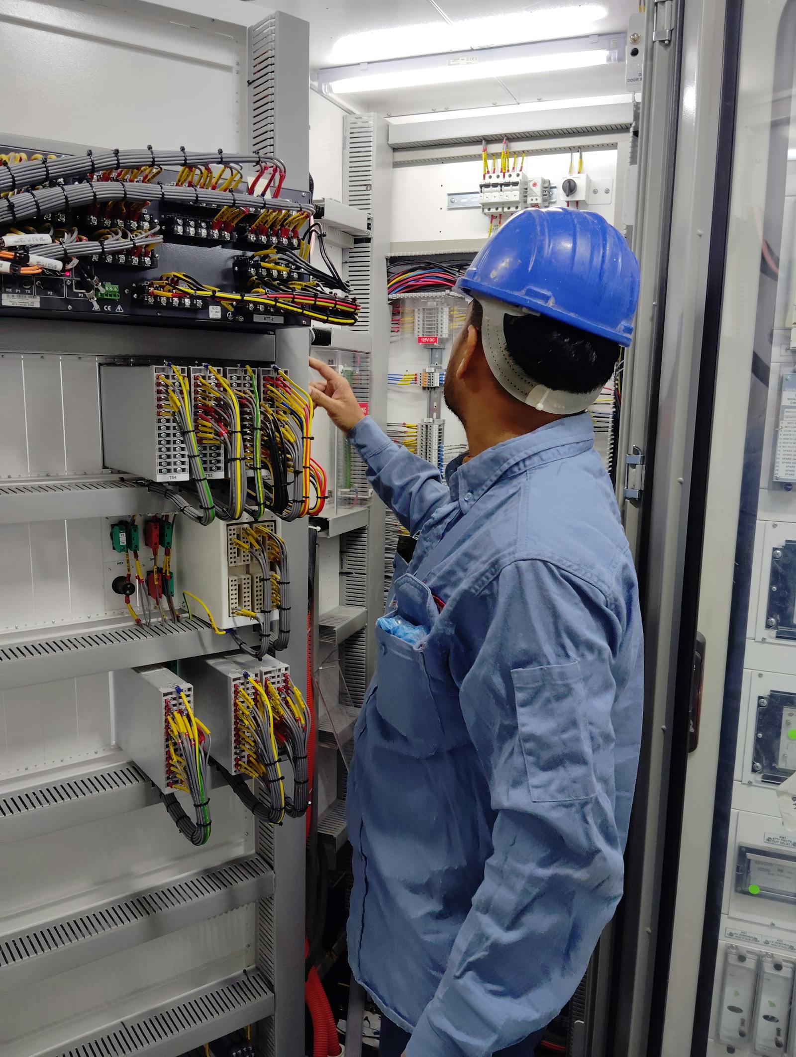 Professional electrician wearing a helmet while working with colored cables