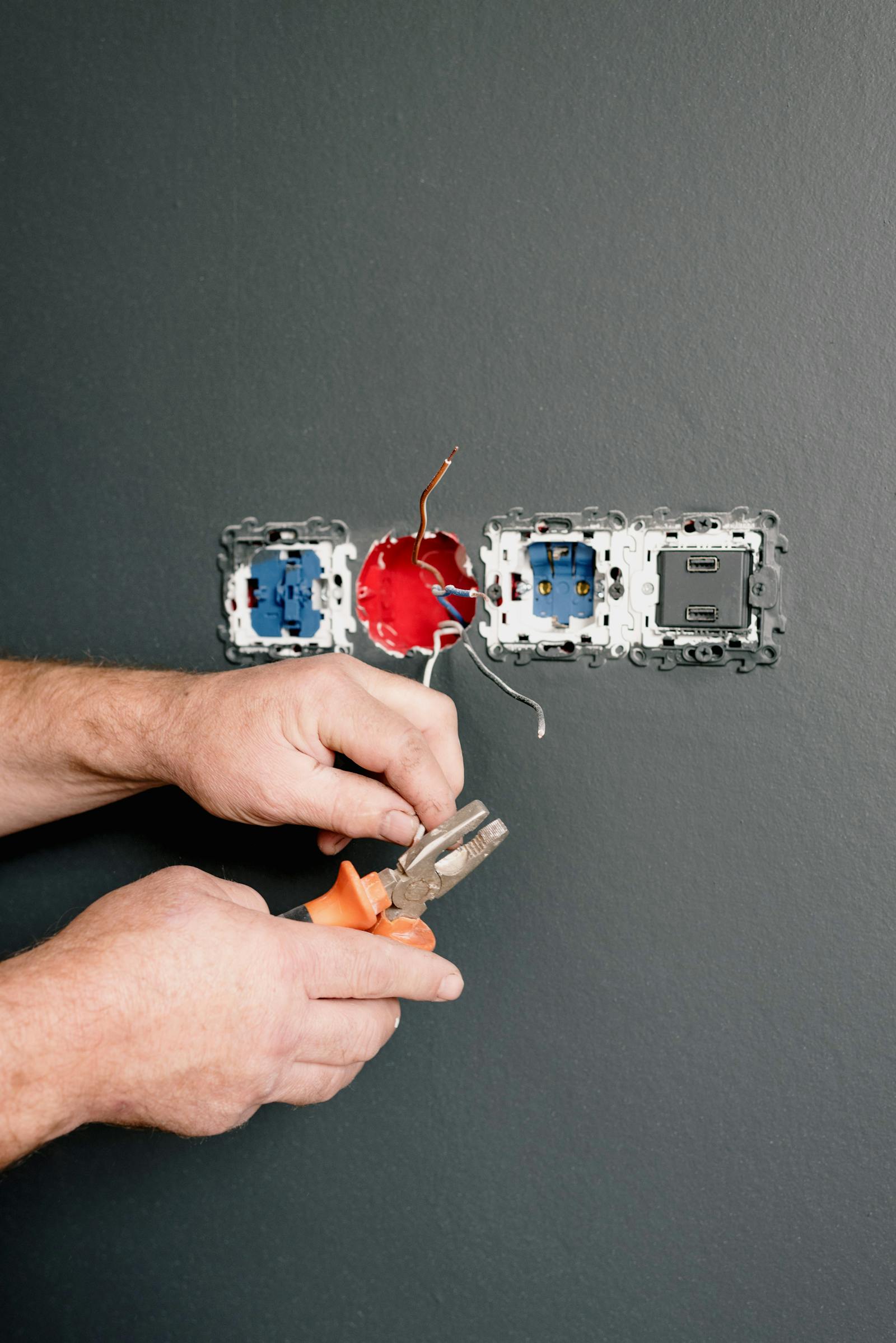 Electrician using pliers to repair AC power plugs and sockets safely