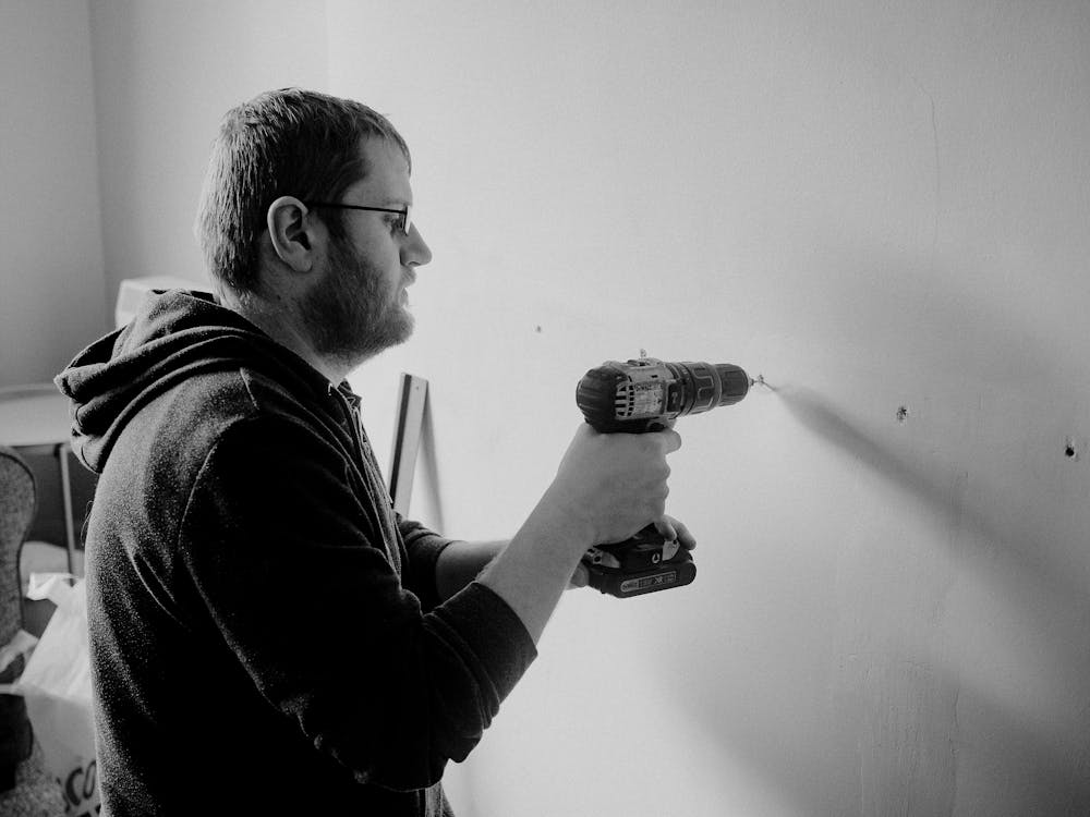 Man using a drill to mount something on a wall after locating studs