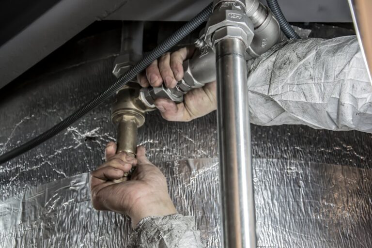 A plumber installing pipe fittings under a sink