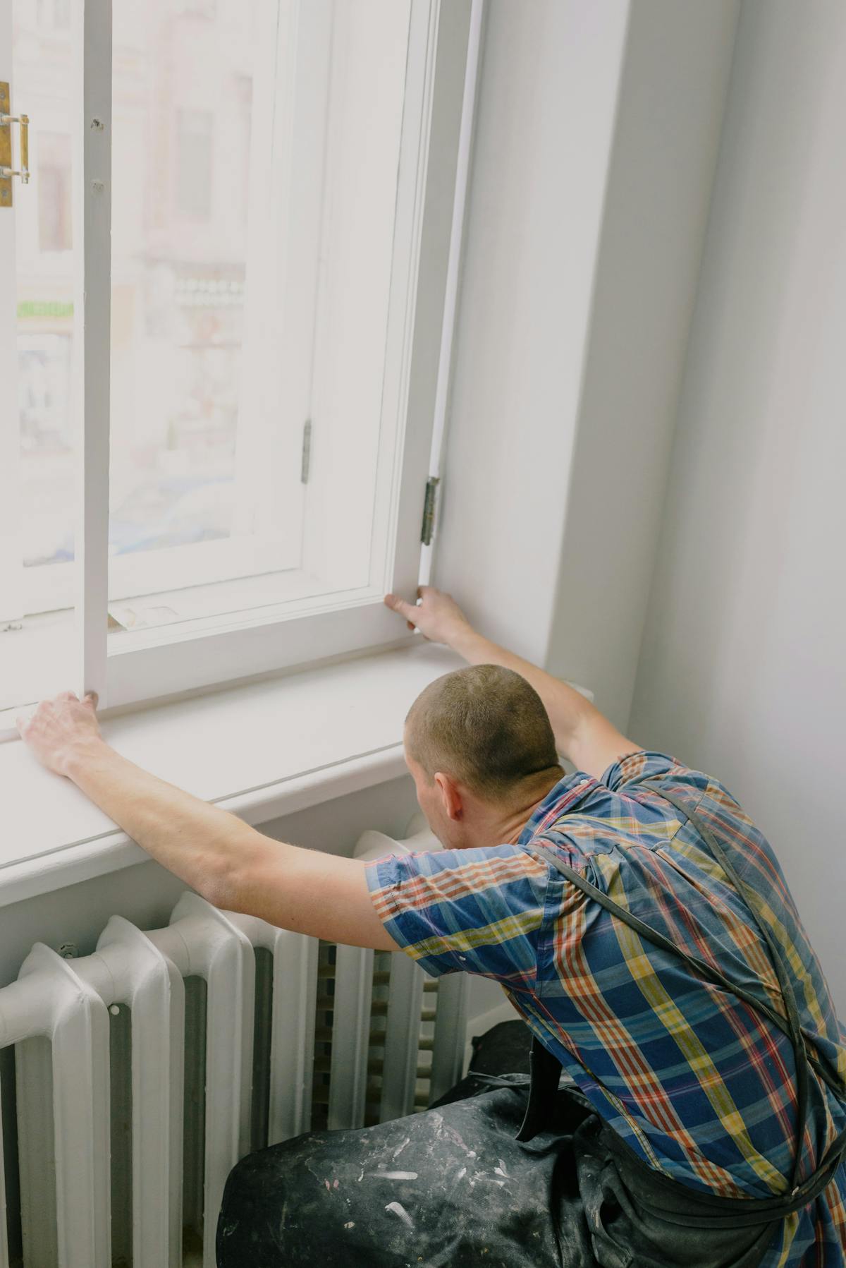 A professional handyman installing a window in a home